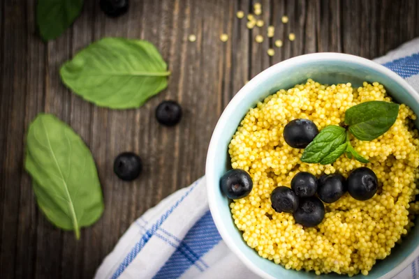 Darı tahıl yaban mersini ve ahşap arka plan üzerinde ham maddeler ile püre.