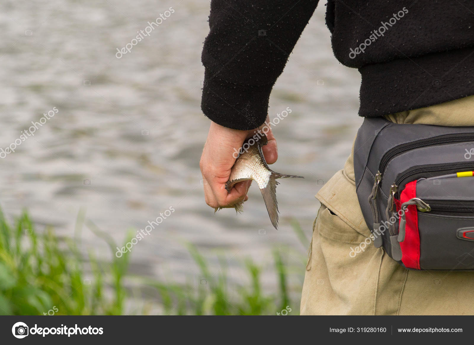 Fisherman Holds Caught Fish His Hand Shore Pond Background