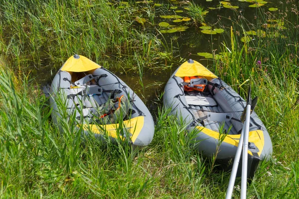 Two inflatable boats moored to the river bank, stand in coastal thickets, one of the boats with oars, the second with a life jacket