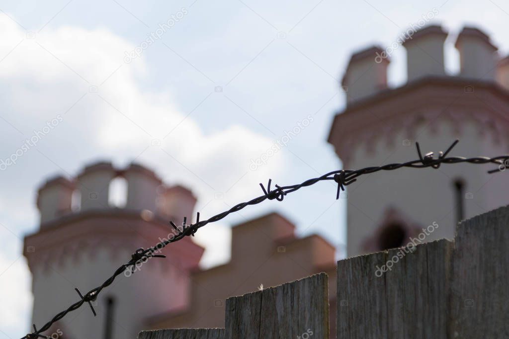 A wooden fence and barbed wire enclose an ancient palace in the medieval gothic style, which is under restoration