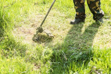 İşçi, çim biçme makinesiyle çim biçiyor. Bir adam çim biçme makinesiyle çimlere bakar..
