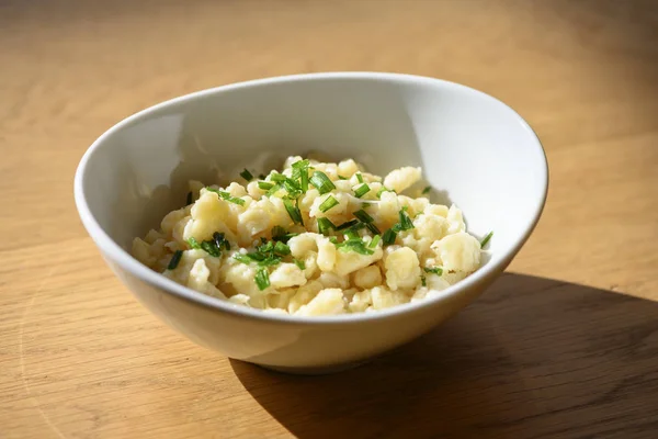 cheese spaetzle or in austria kaesspatzn in white bowl with green chive