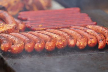 Izgarada nefis sosisler var ve elinde maşayla onları çeviriyor..