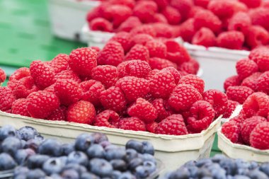 Taze meyve ahududu, çilek ve yabanmersini tezgahtaki kağıt kaselerde. Meyve pazarda satılmak üzere tasarlanmıştır..