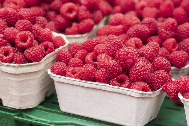 Taze meyve ahududu, çilek ve yabanmersini tezgahtaki kağıt kaselerde. Meyve pazarda satılmak üzere tasarlanmıştır..
