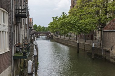 Hollanda 'daki Dordrecht şehrindeki evler arasında su kanalı var. Arka planda taş bir köprü var..