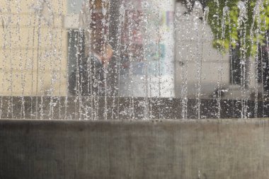 Çeşme suyu damlaları ve arka planda bulanık tampon.