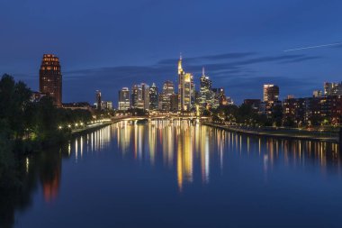 Fotoğraf: Frankfurt 'taki Deutschherren Köprüsü' nden. Gün batımından sonra mavi saatte. Şehir merkezi ve nehir arka planda yanıyor..