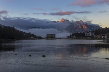 Güzel göl Brais, İtalyan Dolomitleri 'nde gökyüzünün yansıması ve yüzeydeki teknelerle