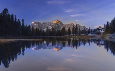 Güzel göl Brais, İtalyan Dolomitleri 'nde gökyüzünün yansıması ve yüzeydeki teknelerle