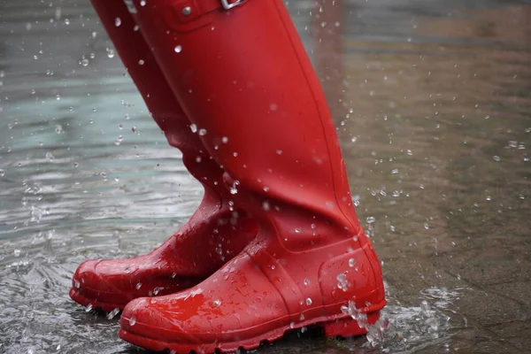 red rubber water boots generating a splash in a water