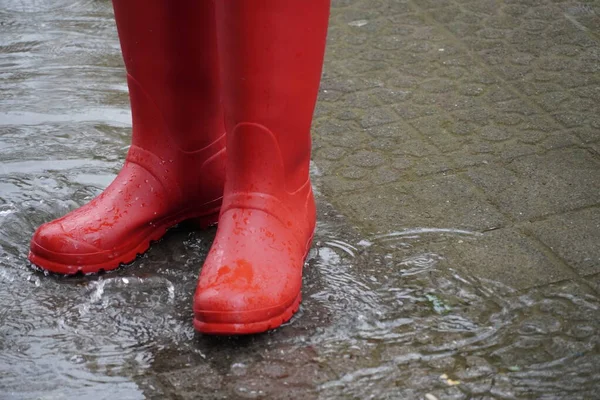 red rubber water boots generating a splash in a water puddle after jumping