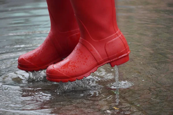 red rubber water boots generating a splash in a water