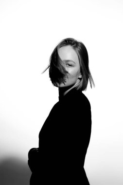 Güzel bir modelin şık siyah beyaz portresi. Beyaz arka planda izole edilmiş. Destansı ışık ve gölgeler.