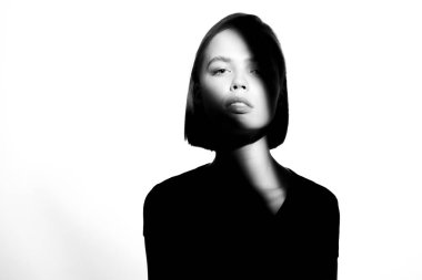 Moda bir güzellik portresi. Beyaz arka planda siyah siluet. Yüzünde ışık lekesi olan bir kız. 