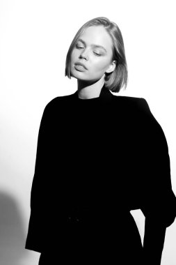 Güzel bir modelin şık siyah beyaz portresi. Beyaz arka planda izole edilmiş. Destansı ışık ve gölgeler.