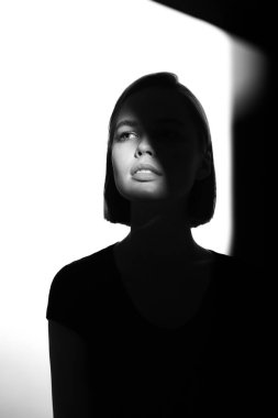 Moda bir güzellik portresi. Beyaz arka planda siyah siluet. Yüzünde ışık lekesi olan bir kız. 