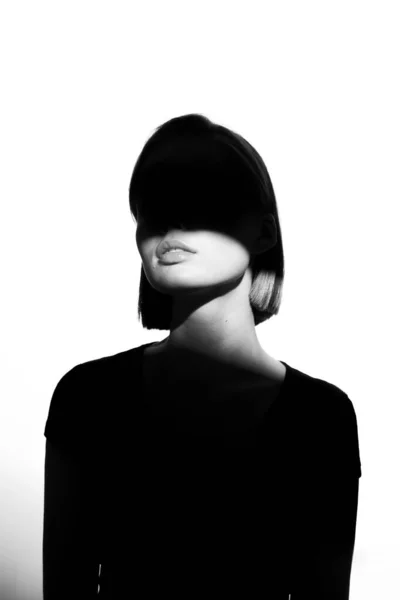 Módní portrét krásy. Černá silueta na bílém pozadí. Dívka s skvrnou světla na tváři. — Stock fotografie