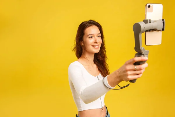 Chica blogger joven con tres ejes estabilizador electrónico gimbal. Hace un selfie y video blog . — Foto de Stock