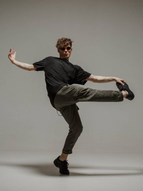 Stüdyoda çağdaş dans eden adam. Tarafsız gri arka plan. Akrobatik bboy dansçısı.