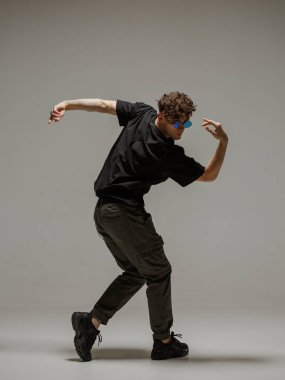 Stüdyoda çağdaş dans eden adam. Tarafsız gri arka plan. Akrobatik bboy dansçısı.