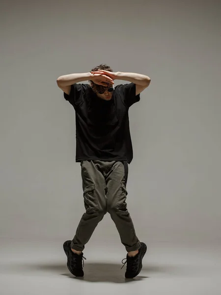 Guy che balla danza contemporanea in studio. Fondo grigio neutro. ballerino bboy acrobatico . — Foto Stock