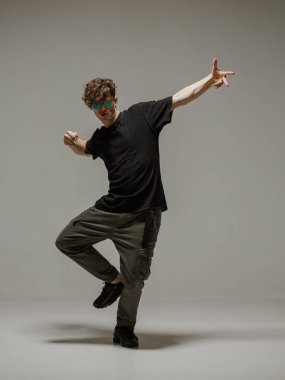 Stüdyoda çağdaş dans eden adam. Tarafsız gri arka plan. Akrobatik bboy dansçısı.