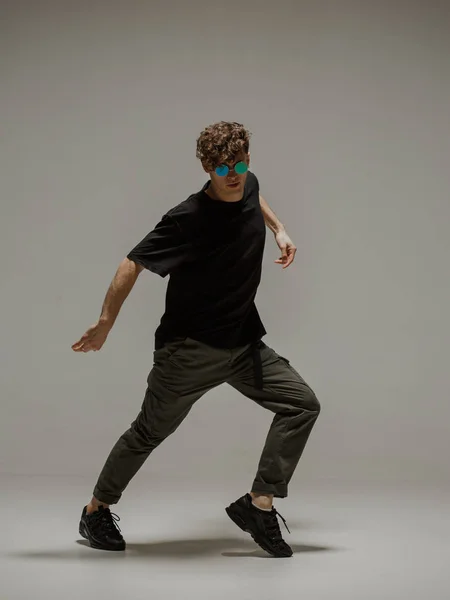 Facet tańczący taniec współczesny w studio. Neutralne szare tło. akrobatyczny bboy tancerz. — Zdjęcie stockowe