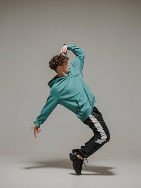 Stüdyoda çağdaş dans eden adam. Tarafsız gri arka plan. Akrobatik bboy dansçısı.
