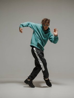 Stüdyoda çağdaş dans eden adam. Tarafsız gri arka plan. Akrobatik bboy dansçısı.