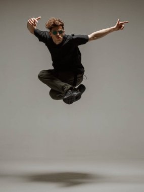 Stüdyoda çağdaş dans eden adam. Tarafsız gri arka plan. Akrobatik bboy dansçısı.