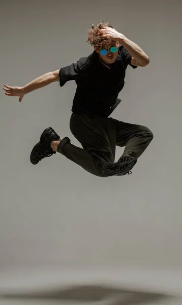 Stüdyoda çağdaş dans eden adam. Tarafsız gri arka plan. Akrobatik bboy dansçısı. — Stok fotoğraf