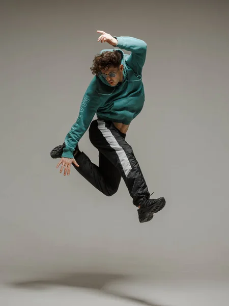 Stüdyoda çağdaş dans eden adam. Tarafsız gri arka plan. Akrobatik bboy dansçısı.