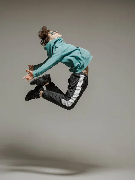 Guy dancing contemporary dance in studio. Neutral grey background. Acrobatic bboy dancer. — Stock Photo, Image