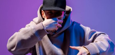 Erkekler neon ışıkta portre çizerler. Kapüşonlu ve şapkalı. Koyu surat. Hip-hop tarzı.