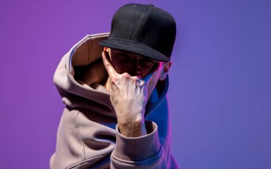 Erkekler neon ışıkta portre çizerler. Kapüşonlu ve şapkalı. Koyu surat. Hip-hop tarzı.