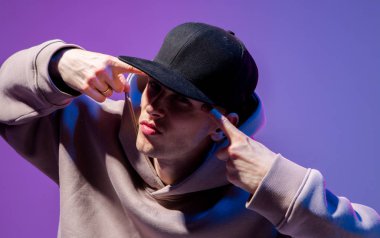 Erkekler neon ışıkta portre çizerler. Kapüşonlu ve şapkalı. Koyu surat. Hip-hop tarzı.