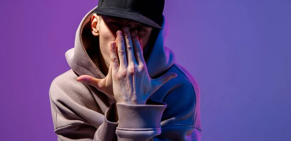 Ritratto maschile in una luce al neon. Sotto con cappuccio e cappello. Faccia scura. Stile hip-hop . — Foto Stock