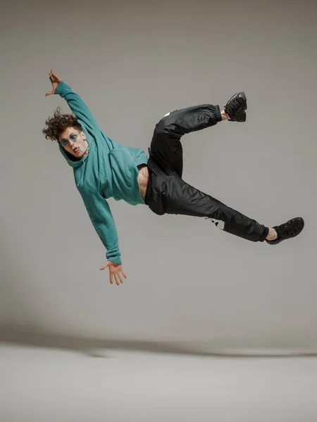 Boy dancing breakdance mid-air in studio. Acrobatic dancer.