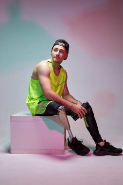 Spor salonunda antrenman yaptıktan sonra protez bacaklı, engelli genç yakışıklı bir adam. Spor kıyafetleri.