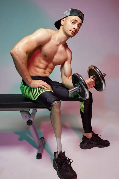 Um jovem homem musculoso com uma deficiência com uma perna protética está treinando em um ginásio com halteres. Cartaz de motivação . — Fotografia de Stock