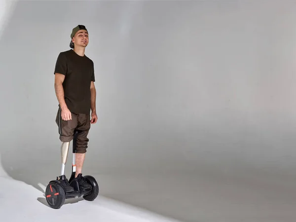Joven discapacitado en hoverboard con prótesis de pierna en el estudio. Luz de sombra . —  Fotos de Stock