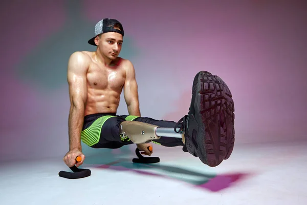 Un giovane uomo muscoloso con disabilità con una gamba protesica si allena in palestra. Manifesto allenamento motivazione . — Foto Stock