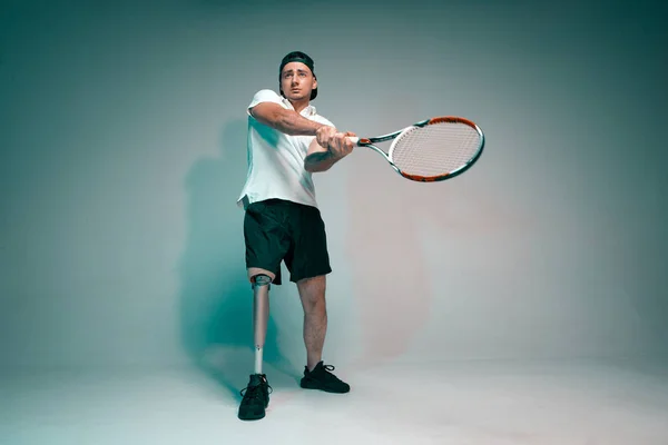 En ung man med ett handikapp med en protes ben spela i tennis. Motivationsaffisch. — Stockfoto