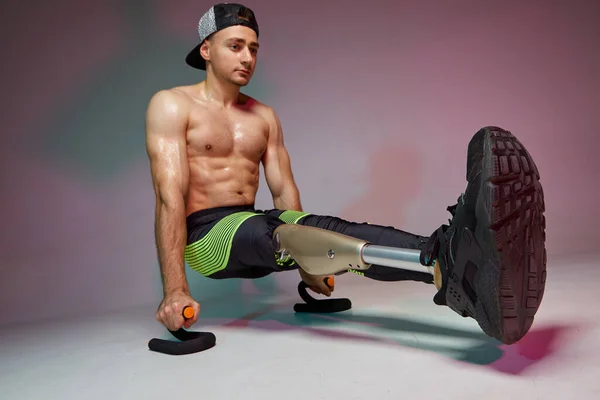 Een jonge gespierde man met een handicap met een kunstbeen is aan het trainen in een sportschool. Motivatie workout poster. — Stockfoto
