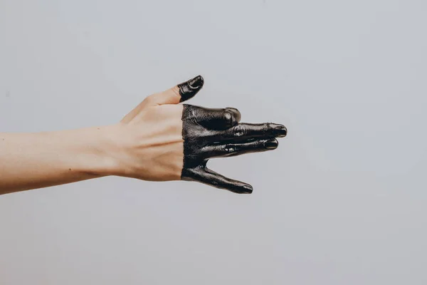 Elegant female hand dipped in black paint on a light background. Isolated. Gesture. — Stock Photo, Image