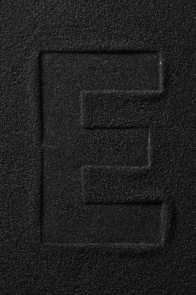Impronta di una lettera spremuta su sabbia nera . — Foto Stock