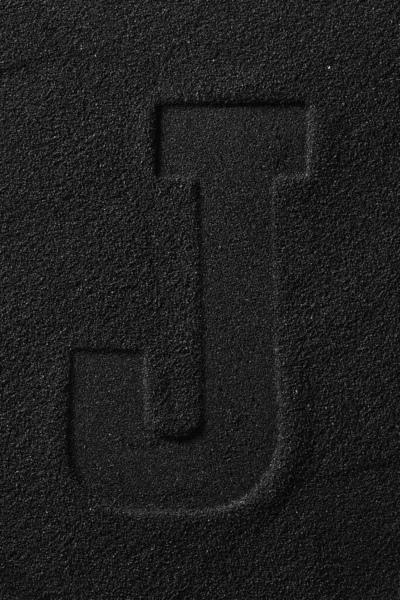 Opdruk van een uitgeperste brief op zwart zand. — Stockfoto