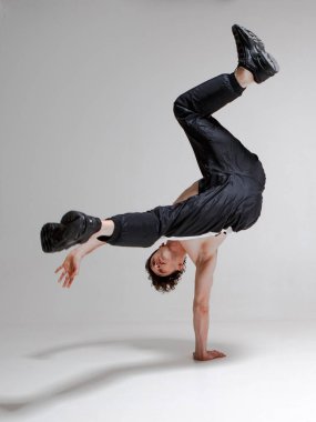 Genç ve zarif bir adam yerde tişörtsüz break dans yapıyor. Karmaşık numaralar. Dövmeli vücut..