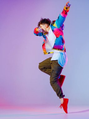 Stüdyoda çağdaş dans eden adam. Neon açık gri arka plan. Akrobatik bboy dansçısı. Break dans dersleri.
